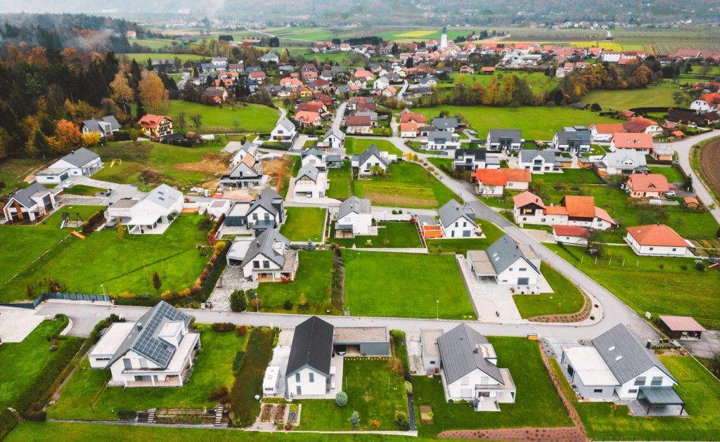 Aerial view, drone flying over new housing development in the country side. Family homes in the suburbs surrounded with forest and green fields.